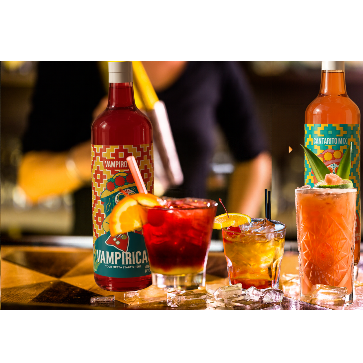 Vampiricas and Cantaricas bottles behind three colorful iced drinks on a bar